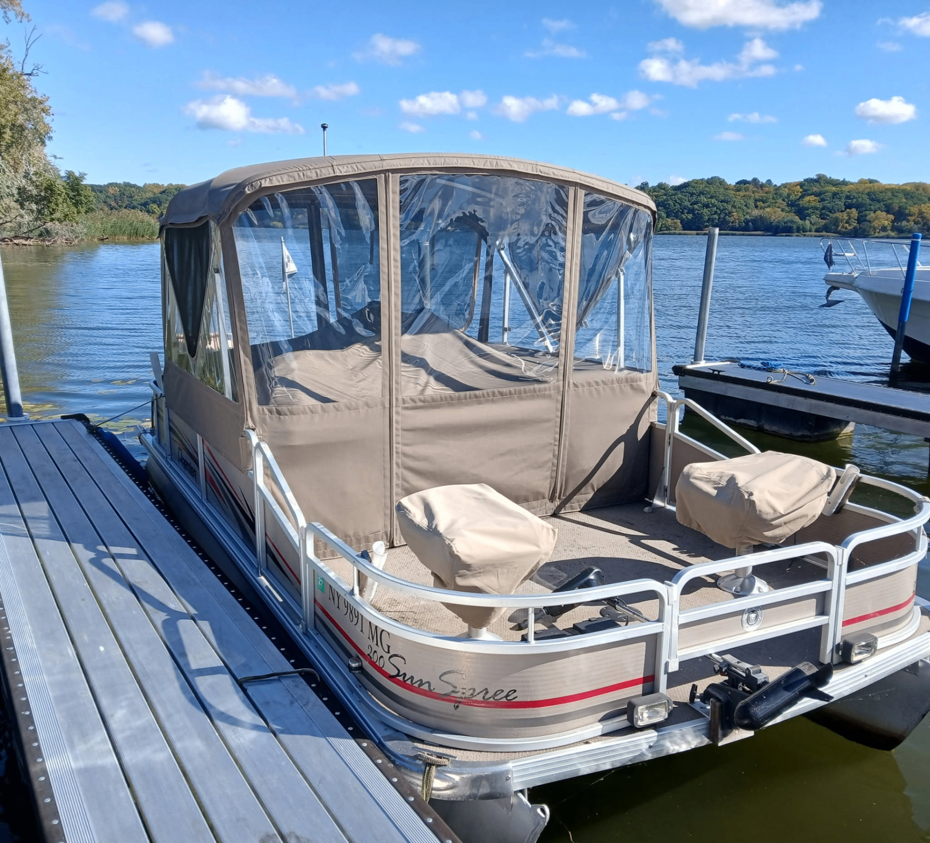 Tan full pontoon enclosure with clear vinyl panels at the dock